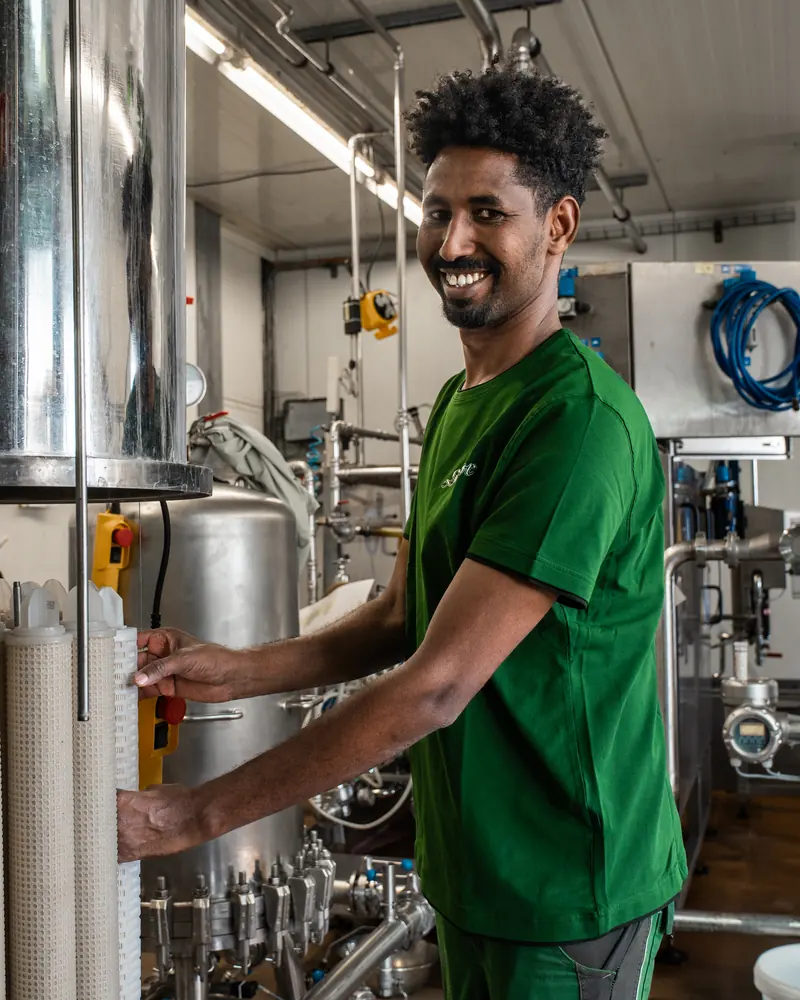 Industriemechaniker an der Filteranlage, lacht in die Kamera