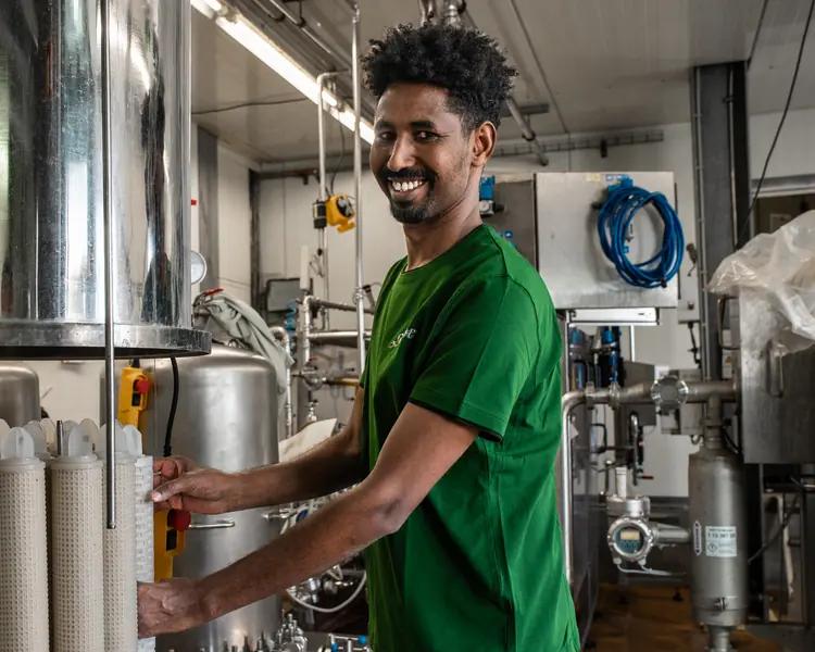 Industriemechaniker an der Filteranlage, lacht in die Kamera